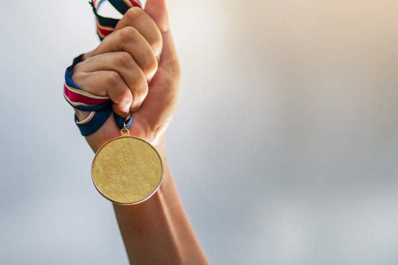 main portant une médaille en or pour les jeux olympiques